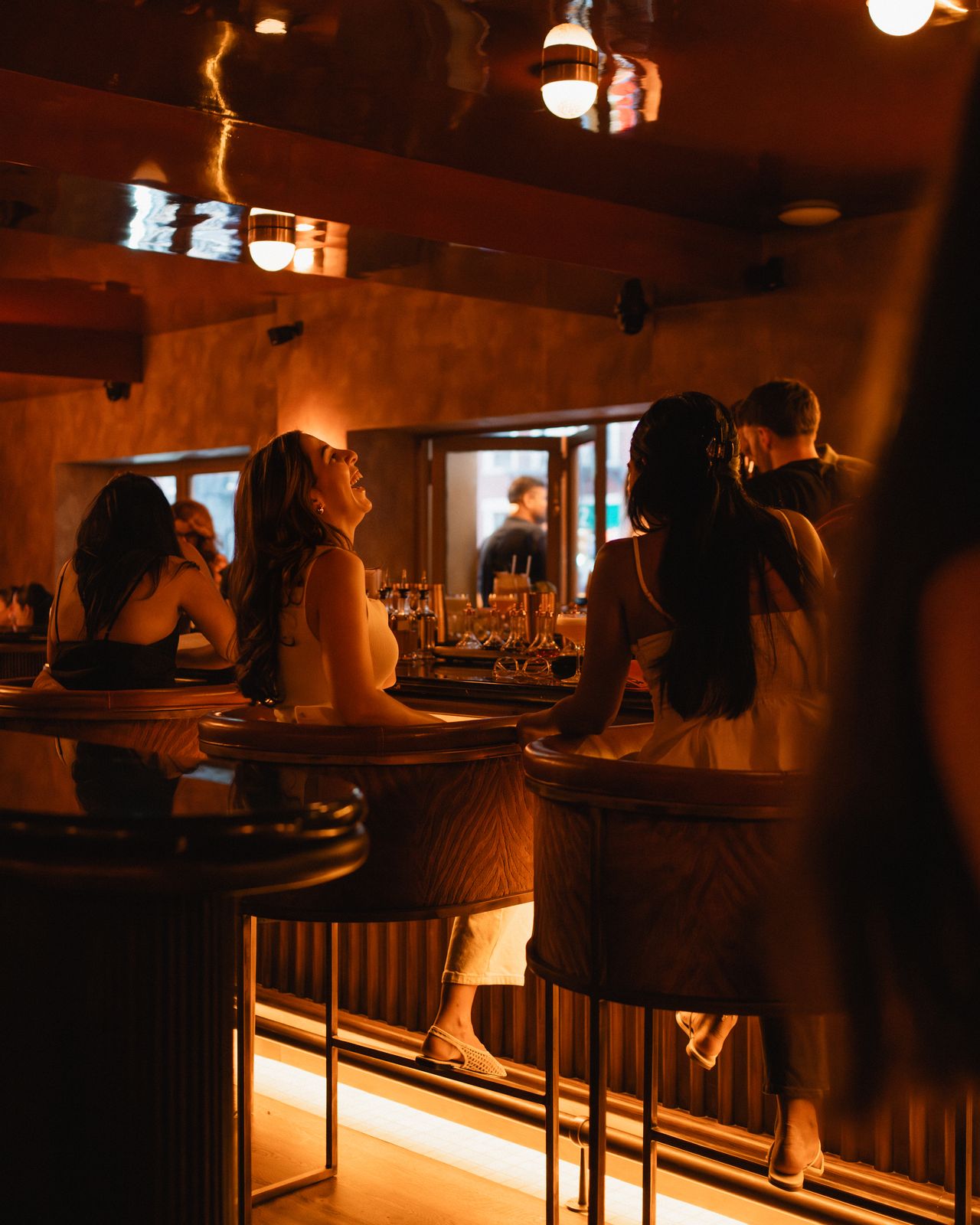 Two women laughing together at the bar on a night out