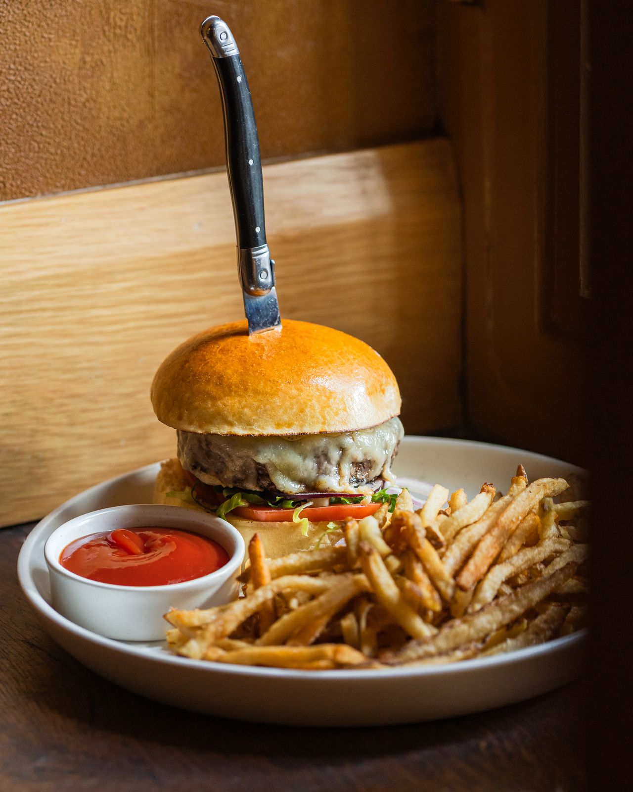 Cheeseburger and fries served with a steak knife through the bun